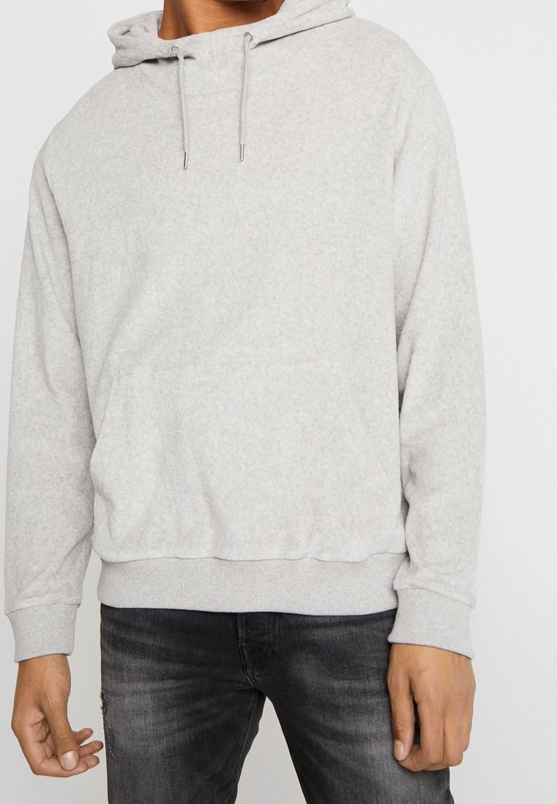 Sudadera gris clara hecha de una tela suave, que cuenta con un bolsillo frontal, capucha con cordón y puños y dobladillo acanalados.