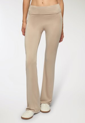 Pantaloni beige a palazzo realizzati in un tessuto liscio e elastico con una cintura larga. Presentano un aspetto pulito e sartoriale e una vestibilità sicura intorno alle gambe.