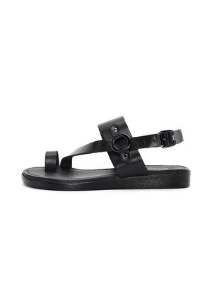 Black leather sandal with an open toe, adjustable ankle strap, circular hardware detail, and a textured flat sole. Simple and modern design.