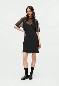 Vestido preto com um design ajustado, mangas curtas transparentes e um decote em V profundo, feito de um tecido leve com uma textura suave.
