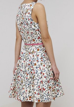Bloemenjurk met een witte basis, versierd met kleurrijke bloemen en vogels. Mouwloos ontwerp, getailleerde taille met een roze riem, uitlopende rok.