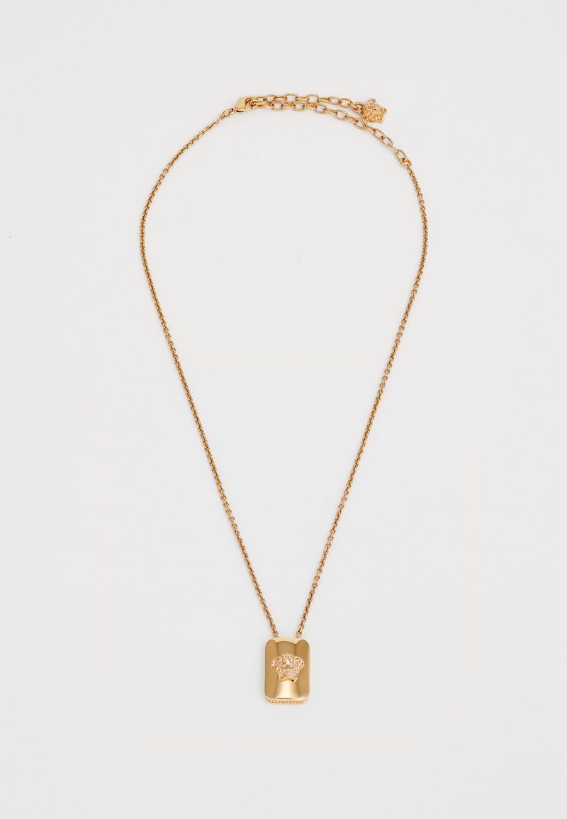 Zelta ķēdes kaklarota ar taisnstūrveida piekariņu, kurā attēlota izvirzīta Medūzas galva, un regulējams aizdare ar mazu Medūzas šarmu.