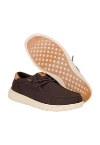 Scarpe in tela marrone con suola in gomma, dotate di accenti beige, punta rotonda e design con lacci. La suola presenta una superficie texturizzata e decorata.