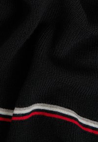 Tessuto a maglia nero con un motivo testurizzato, caratterizzato da una striscia orizzontale rossa, bianca e blu navy lungo il bordo.