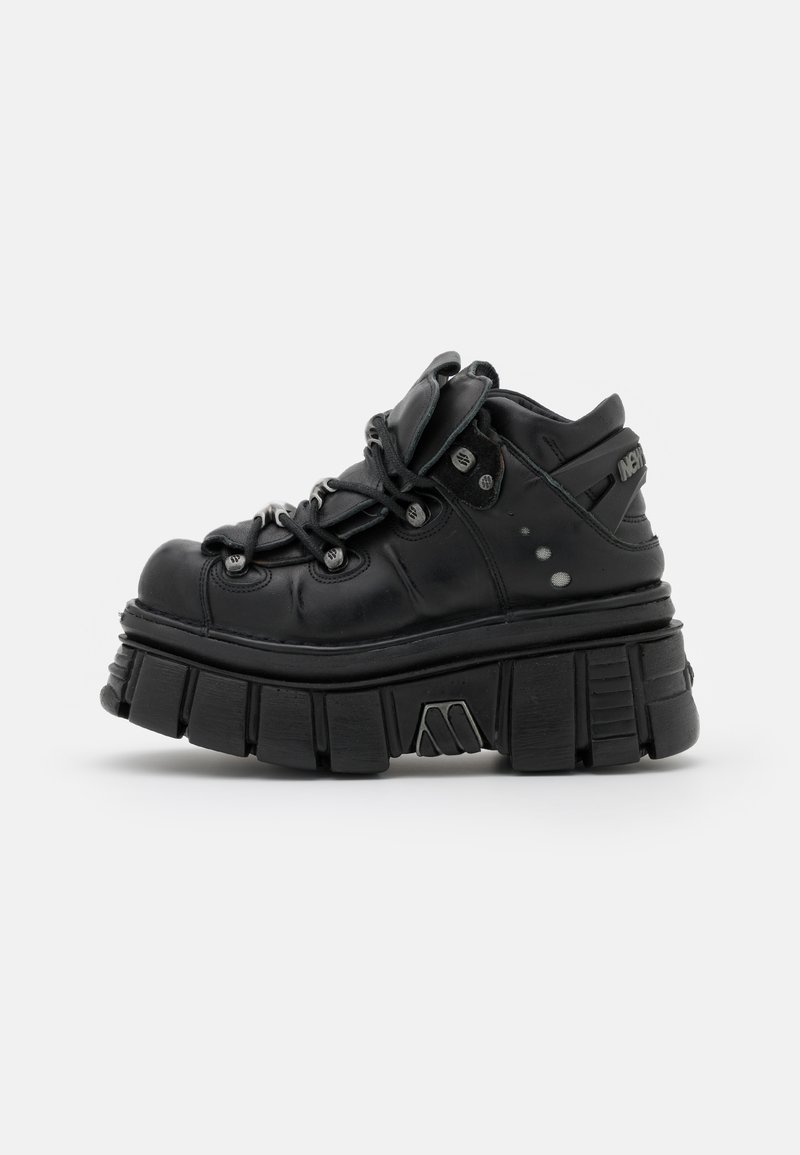 Black chunky platform sneakers with rounded toe, textured leather upper, padded tongue, and metallic accents; thick ridged sole design.