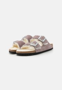 Sandalen met nepbont voering, voorzien van twee verstelbare gespen, paarse suede bovenkant, kurken tussenzool en zwarte rubberen buitenzool.