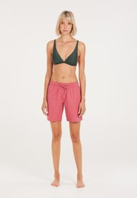 Zelený bikiny top s ribovaným dizajnom a výstrihom do V, spárovaný s ružovými plavkami s šnúrkou, ktoré majú ľahký materiál a voľný strih.
