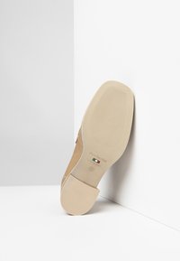 Beige schoen met een ronde neus en een gladde afwerking. De zool heeft een gestructureerd oppervlak met groeven en bevat de branding: "Nero Giardini, Made in Italy."