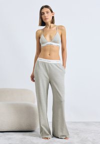 Grå bomullsbralette med tynne stropper og logobånd, kombinert med matchende løstsittende, høy midje grå bomullssvetters med logobånd.