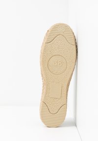 Semelle de chaussure en caoutchouc, beige avec un profil texturé, affichant la taille 38 et les détails de fabrication, sur un fond blanc.