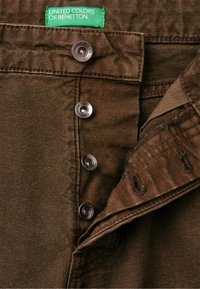 Br�ązowe spodnie z denimu o teksturowanym wykończeniu, z srebrnymi metalowymi guzikami i zieloną metką z napisem "United Colors of Benetton".