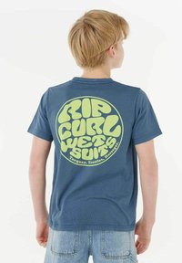 T-shirt en coton bleu avec un grand graphic circulaire jaune-vert portant le texte "RIP CURL WETSUITS". Manches courtes et design col rond.