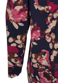 Top floreale a maniche lunghe con sfondo blu navy e fiori rosa e crema. Realizzato in tessuto morbido, presenta dettagli cuciti sulle maniche.