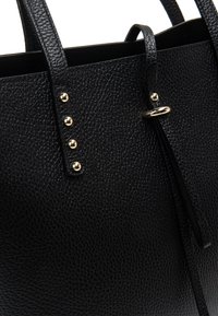 Černá kožená kabelka s texturovaným povrchem, zdobená zlatými akcenty a cvočky, s dvojitými horními uchy a plochým zavíráním.