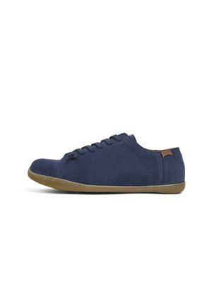 Zapatillas de ante azul marino con un perfil bajo, puntera redonda y suela de goma plana. Presentan un diseño sencillo con cordones y una pequeña etiqueta de acento marrón.