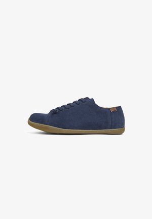 Marineblå ruskinds sneakers med lav profil, rund tå og flad gummisål. Har et simpelt snørebåndsdesign og et lille brunt accentmærke.