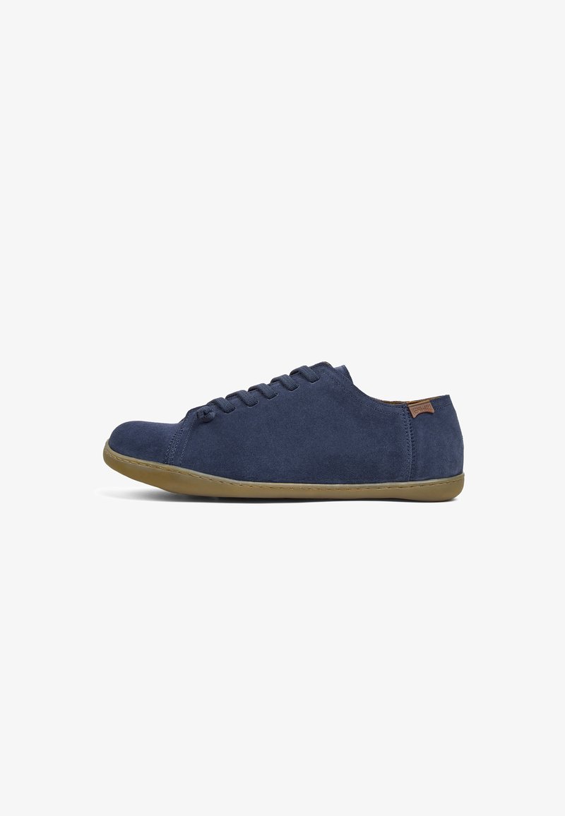 Navy suede sneakers with a low profile, round toe, and flat rubber sole. Features a simple lace-up design and a small brown accent tag.