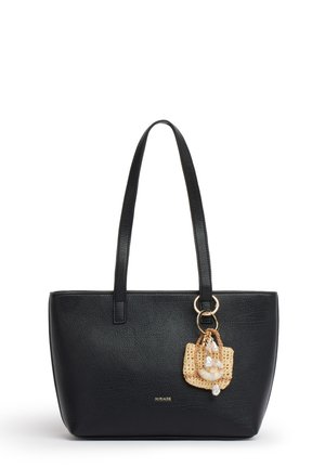 Sac cabas en cuir noir avec de longues anses, petit charm tissé décoré de coquillages et de perles suspendu à une anse.
