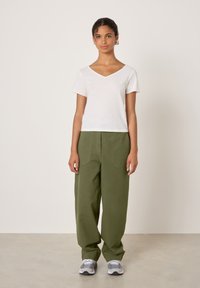 Valge puuvillane V-kaelusega T-särk, mis on kombineeritud lõdvalt istuvate oliivroheliste pükstega. Komplekti lõpetavad hallid spordijalatsid. Lihtne disain ja kerge materjal.