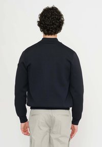 Pullover blu navy lavorato a maglia con colletto, presenta maniche lunghe e una finitura testurizzata. La vista dal retro mostra l'etichetta sulla manica sinistra e orlo a coste.