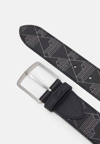 Curea din piele neagră cu un model geometric gri și o cataramă rectangulară argintie. Prezintă un finisaj texturat și mai multe găuri de ajustare.