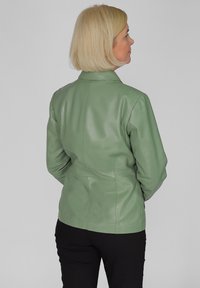 Mintgroene leren jas met een slim-fit ontwerp, lange mouwen en een eenvoudige kraag, getoond vanaf de achterkant met een gladde textuur.