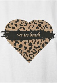 Diseño de corazón con estampado de leopardo beige sobre un fondo blanco, con el texto "venice beach" en negro sobre un acento de pincelada gruesa.