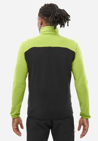Fleece jacket featuring a black lower body, lime green upper portion, high collar, and textured fabric. Designed for outdoor activities.