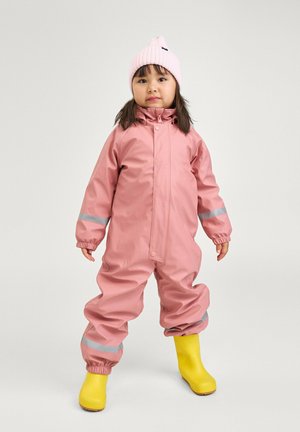 Un ensemble de pluie rose imperméable avec des accents réfléchissants, des poignets élastiques et une fermeture à bouton-pression à l'avant, associé à des bottes en caoutchouc jaunes et un bonnet en tricot rose.