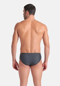 Bañadores de hombre en gris oscuro con una textura suave y mate, que presentan un diseño sencillo de corte moderado y una cintura de tiro bajo.