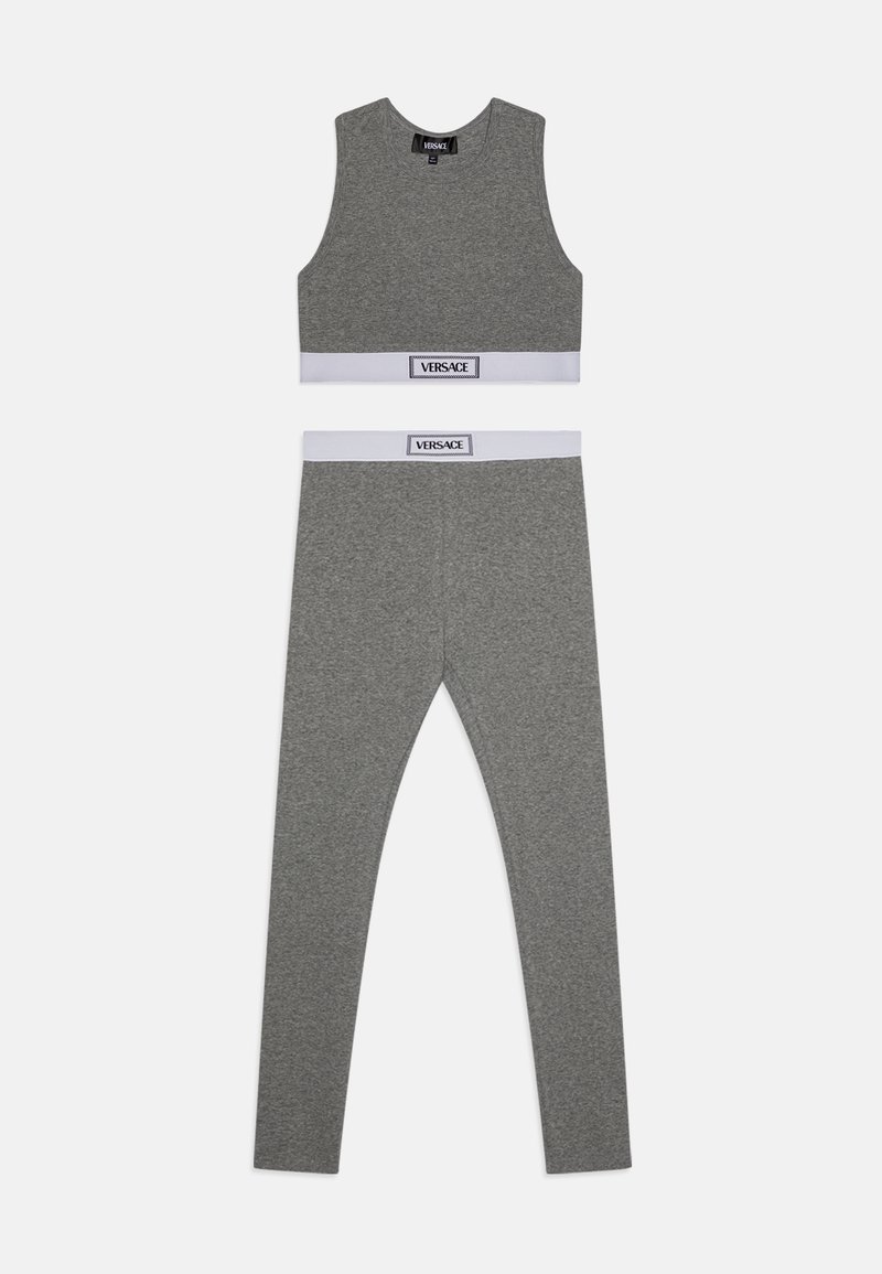 Sivý dvojdielny športový set vyrobený z mäkkej tkaniny. Bezrukávový crop top s bielym pásom a zodpovedajúce legíny s logom na páse.