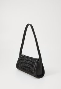 Sac à main en cuir noir avec une texture tissée, de forme rectangulaire, une fine bandoulière et une fermeture éclair. Fini doux avec des accents angulaires.
