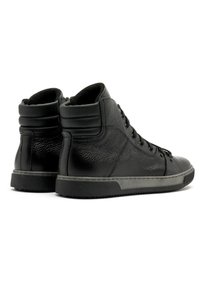 Czarne trampki za kostkę wykonane z fakturowanej skóry, z okrągłym noskiem, wyściełanym kołnierzem i gumową podeszwą z przeszytym brzegiem.