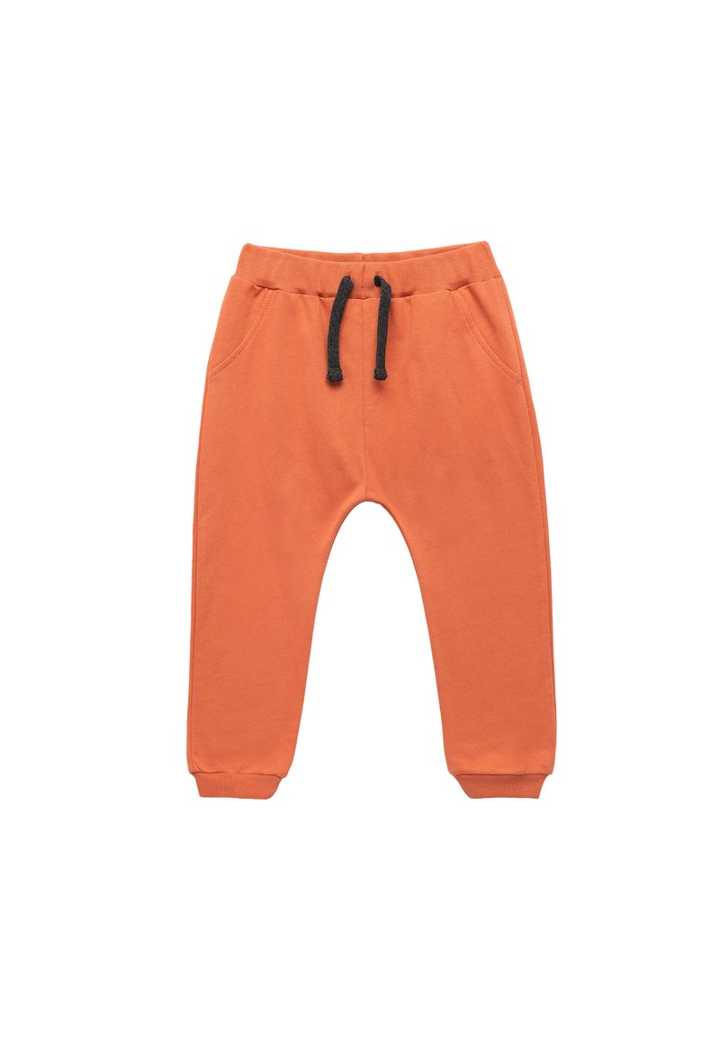 Pomarańczowe dresy wykonane z bawełny, z bocznymi kieszeniami, elastycznym pasem z czarnym sznurkiem oraz zwężanymi mankietami.