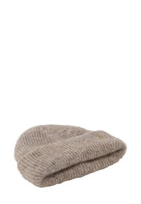 Beżowa, dziana wełniana czapka beanie z zagiętym brzegiem i małym, okrągłym metalowym logo z boku, izolowana na białym tle.