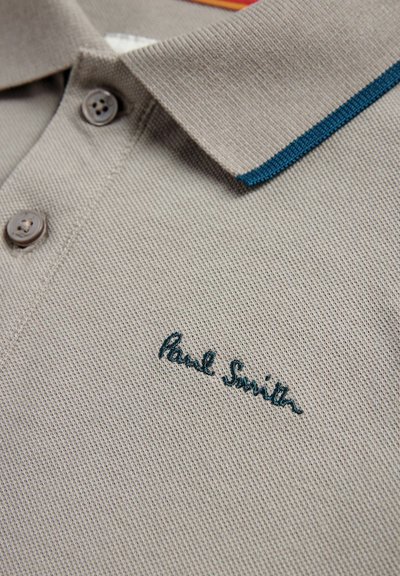 Sivá polo košeľa s textúrovanou tkaninou, s tyrkysovým akcentom na golieri a hnedými gombíkmi. Vyšívané logo znie "Paul Smith."