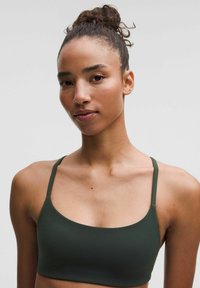 Bralette verde oliva con tirantes finos, diseño sin costuras, textura suave y forma simple y minimalista, adecuada para el uso diario.