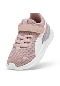 Baskets de sport en mesh rose clair avec des accents blancs, tige texturée, lacets élastiques et sangle Velcro. Équipées d'une semelle blanche rembourrée.
