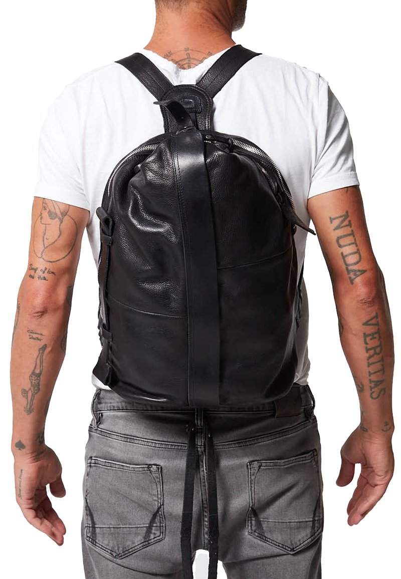 Mochila de cuero negro con correas ajustables, forma redondeada, textura suave y cierre central con cremallera. Presenta un diseño minimalista.