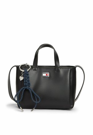 Sac cabas en cuir noir avec poignées courtes, bandoulière amovible, petit logo Tommy Jeans, et porte-clés tressé bleu avec breloque en forme de cœur en métal.