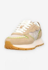 Tan suède sneaker met lichte meshpanelen, limoen groene stiksels, witte veters en een gumrubberen zool. Bevat het label "MEISJES RENNEN SNELLER" op de tong.