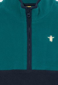 Pulover din fleece, într-o nuanță de teal și albastru marin, cu închidere prin fermoar pe jumătate și un mic design brodat cu un animal pe piept. Textură moale.