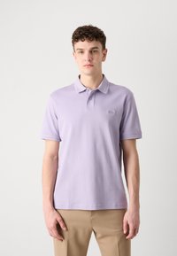 Polo tričko s krátkym rukávom v svetle levandulovej farbe, vyrobené z mäkkej bavlny, s klasickým golierom a jemným logom vyšitým na hrudi.