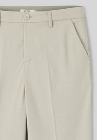 Pantalon taillé beige avec une fermeture à bouton, des poches latérales et une texture diagonale subtile. Design à jambes droites.