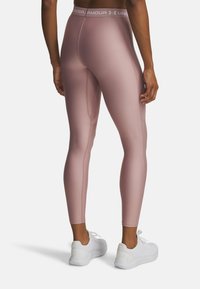 Rosa Sportleggings mit glatter Textur, ausgestattet mit einem Logo-Bund und Seitennähten, kombiniert mit weißen Turnschuhen.