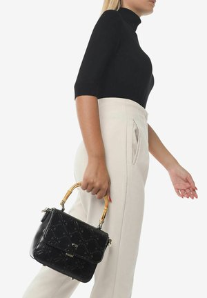 Borsa in pelle nera con motivo embossato, manico in bambù e hardware argentato. Abbinata a una blusa nera e pantaloni beige a vita alta.