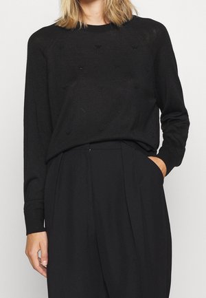 Pull en tricot noir avec un col rond, des manches longues et des motifs texturés subtils. Matière douce avec une coupe décontractée.