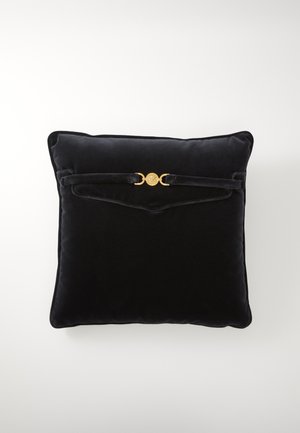 Black velvet square cushion with rounded edges, featuring a gold circular accent and strap detail on the front. Soft texture.