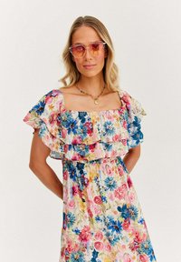Kwiecista sukienka maxi z kwadratowym dekoltem, falbaniastymi rękawami oraz wielokolorowym wzorem z różowymi, niebieskimi i żółtymi kwiatami.