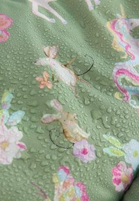 Tissu avec des gouttes d'eau, présentant des illustrations de souris et diverses fleurs colorées sur un fond vert.